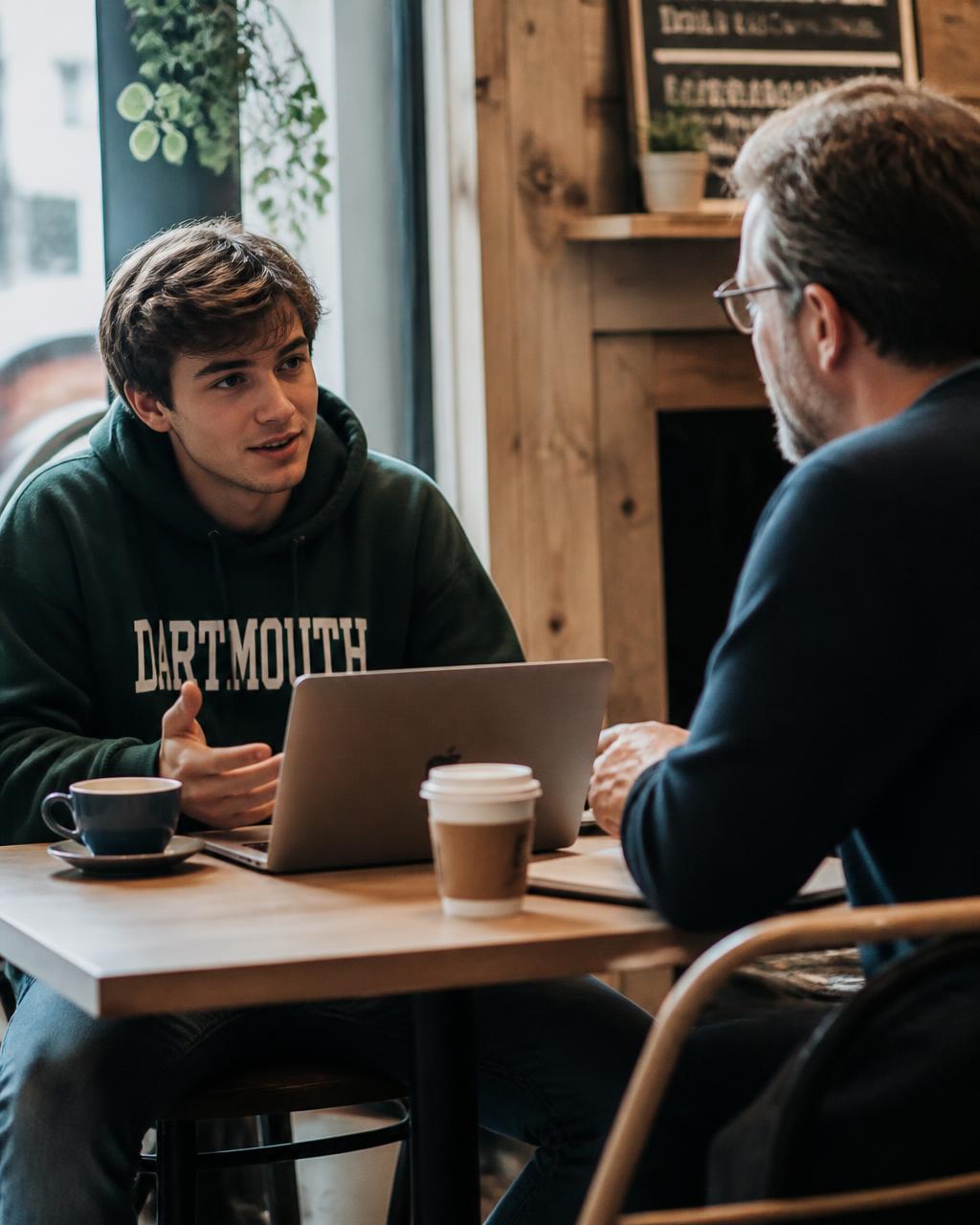 A student in conversation with a professional over coffee